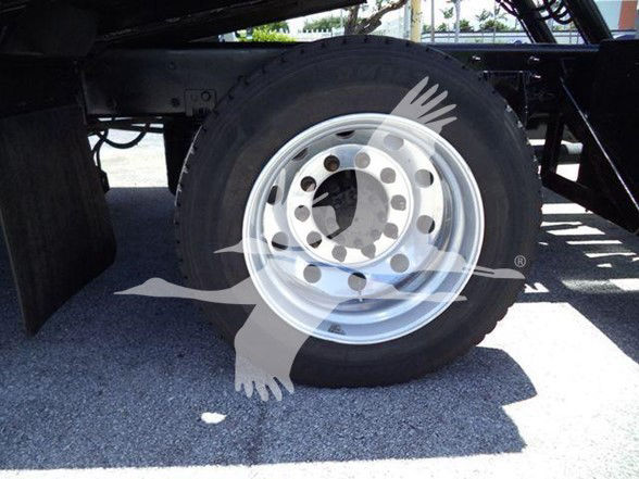Truck wheel and fender area showing alloy wheel and tire mounted on heavy-duty axle.