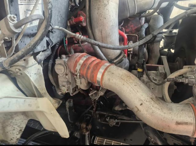 Truck engine bay showing air intake hose with orange clamp and engine components.