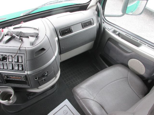 Truck cab interior showing dashboard, steering area, glove box, and passenger seat.