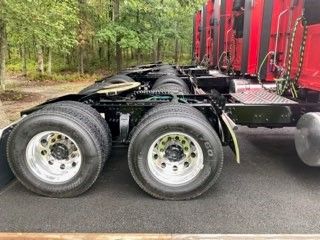 Dual rear truck axles with wheels and tires, part of a Western Star truck chassis. Visible are metal frames, leaf springs, and mounting areas under a cabless section.