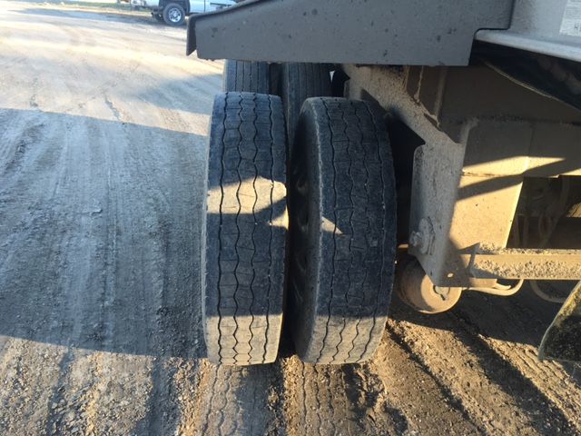 Two rear trailer tires mounted side by side on a Trail King trailer showing wheel hubs and suspension components