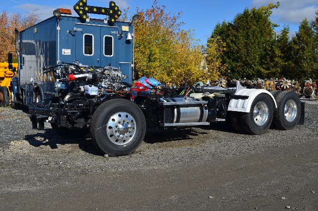 2017 Western Star 5700 XE cabover truck chassis with blue cab and exposed drivetrain, rear wheels, and engine components visible.