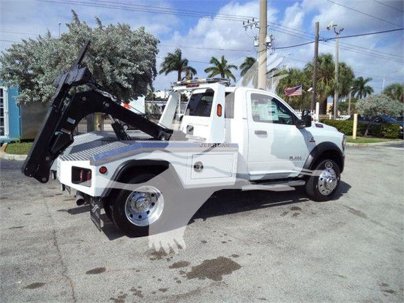 2023 Ram 4500 SLT tow truck with crane/loader hitch and dual rear wheels, white exterior, side view showing cab and service compartments.