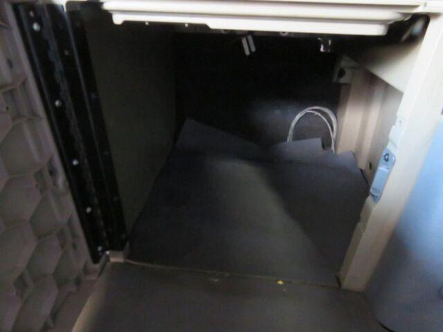 Cabinet or storage area inside a Freightliner Cascadia Evolution truck engine bay showing a dark interior with cables.