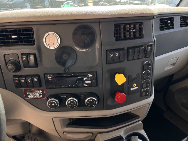 Peterbilt 579 truck dash interior showing control panel with knobs, vents, and a yellow and red emergency switches.