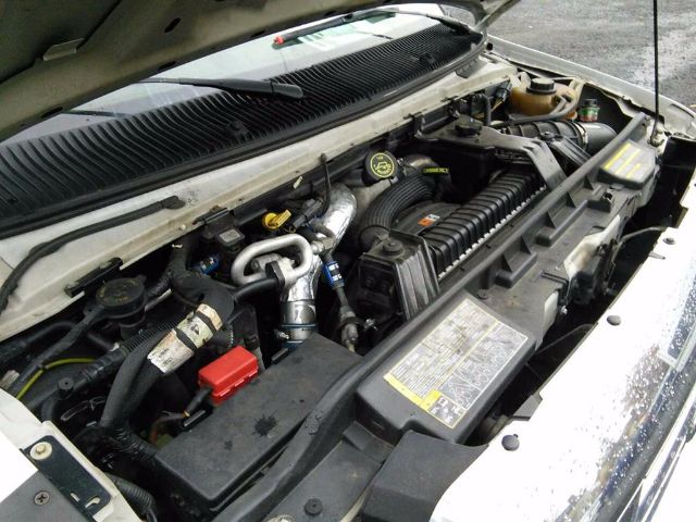 Ford E-450 engine bay showing battery, hoses, air intake, and radiator components.