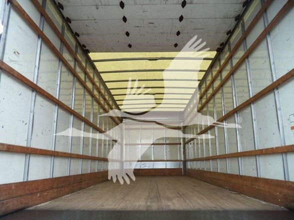 Inside a long empty truck box showing wooden side rails and metal walls.