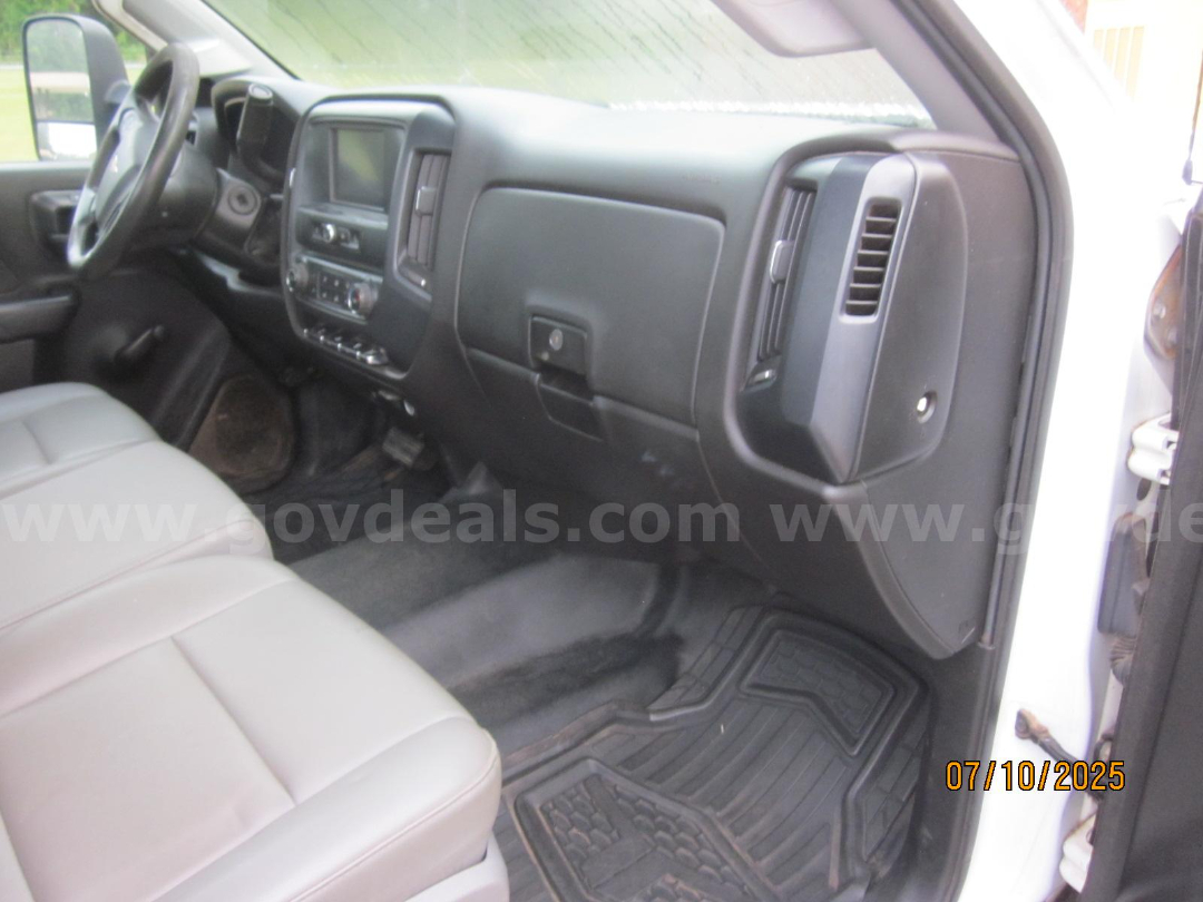 Chevrolet Silverado 3500HD interior dashboard and front seats, black plastic panels, center console, cargo floor mat visible from passenger side.