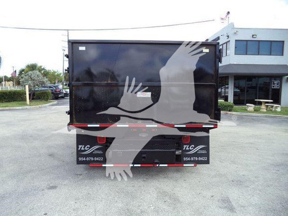 Rear view of a black Ford E-450 dump truck with tailgate and rear fender panels; faint text on bumper areas and reflective stripes.