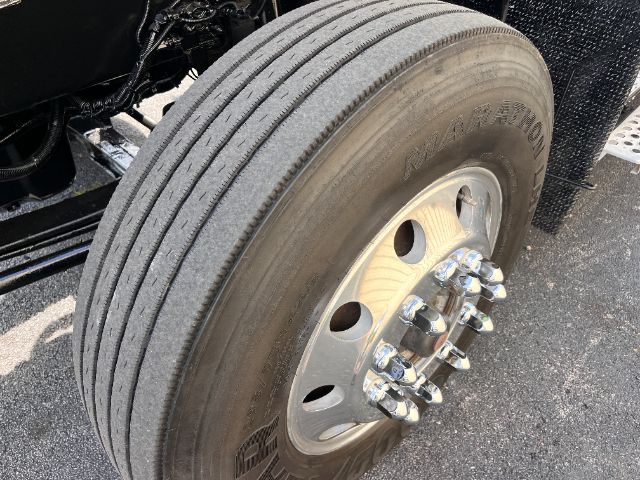 Wheel and tire of a Kenworth truck showing dual rear axles and a 5-lug hub with chrome lug nuts; tread visible on Kumho/Kata? tire with multiple grooves.
