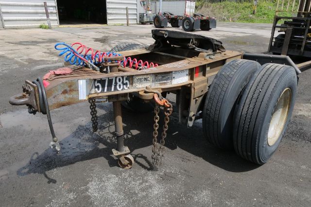 Fruehauf ELFI dolly trailer chassis with dual rear wheels and coiled air lines, rusty frame, chains, and towing hitch.
