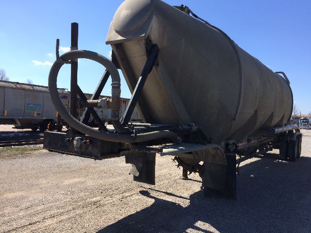 Pneumatic dry bulk trailer showing circular inlet hoses and cylindrical tank on a dual-axle chassis with frame and support stands.