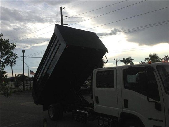 Dump body truck bed tilted on a white cab medium-duty truck showing 14 ft Advanced Fabricators dump body.
