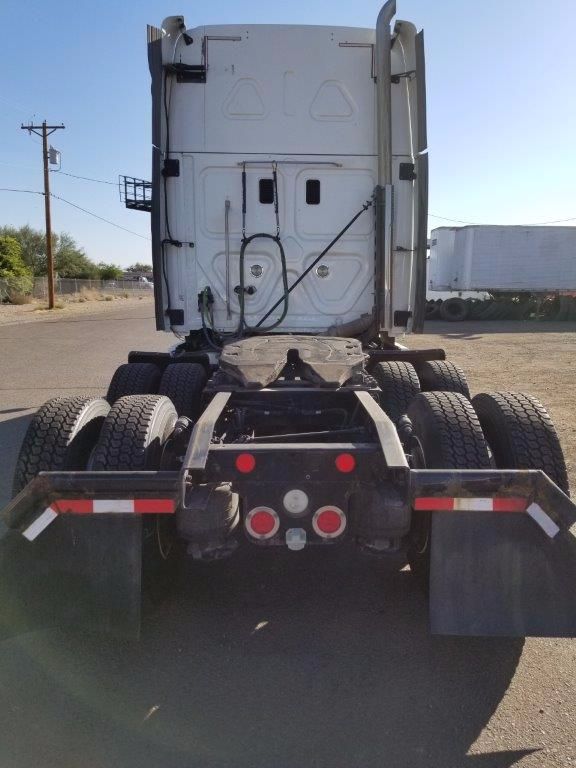 Rear view of a Freightliner Cascadia tractor with dual rear axles and fifth wheel plate, showing taillights, safety reflective strips, and mud flaps.