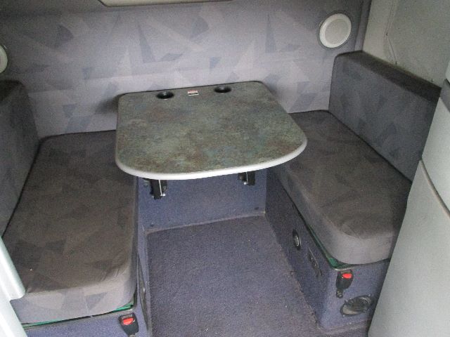Volvo 2012 sleeper cab interior with rear seating area, small table, and fabric cushions.