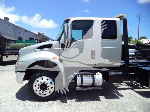 Truck cab of a 2022 International MV with a silver paint job and a side step, showing the front wheel, fuel tanks, and door.