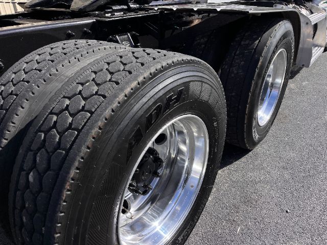 Dual rear tractor tires on a Peterbilt 579 daycab truck, chrome rims, tread visible, part of the undercarriage and fender area.