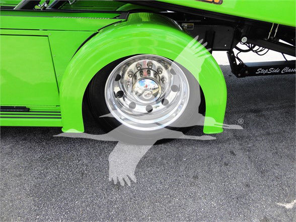 Green Peterbilt 337 front wheel well with chrome hubcap and printed decals near ground shadow