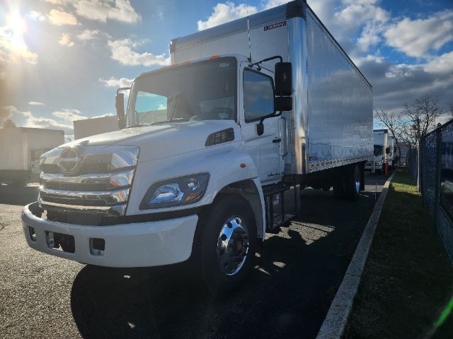 Box truck with white cab and large aluminum cargo box, front grille and headlights visible, dual rear wheels, parked in lot.