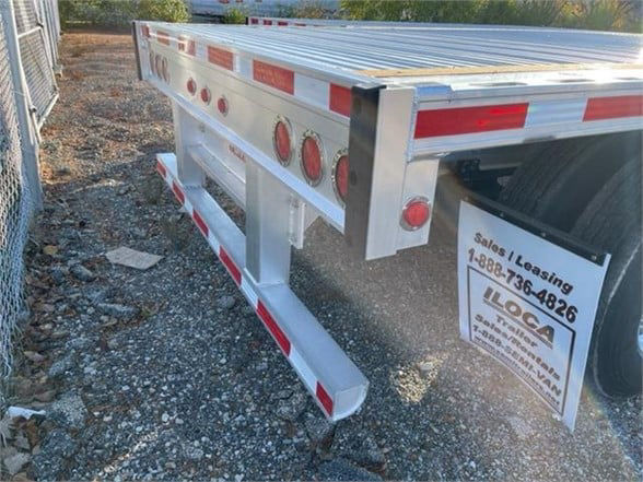 Flatbed trailer rear view showing reinforced aluminum frame and rear bumper with red reflectors; 'Sells / Leasing' sign on side panel; stock number 561775; Fontaine REVOLUTION 52/53FT aluminum trailer branding not visible.