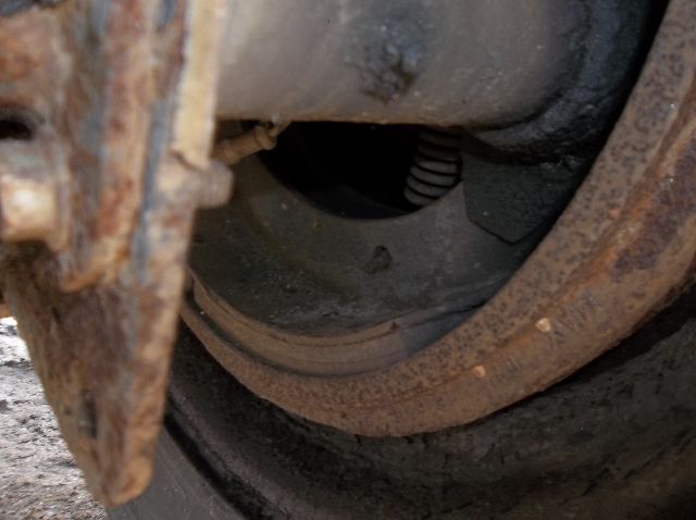 Trailer wheel assembly with visible rust and drum brake components in close-up.