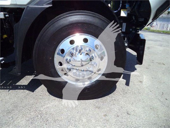 Wheel and front axle of a 2023 Mack MD6 with polished chrome hub and lug nuts visible.