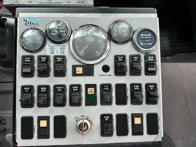 Isuzu NPR-HD truck dash panel with multiple gauges and switches, including RPM gauge, engine temperature, and various indicator lights.