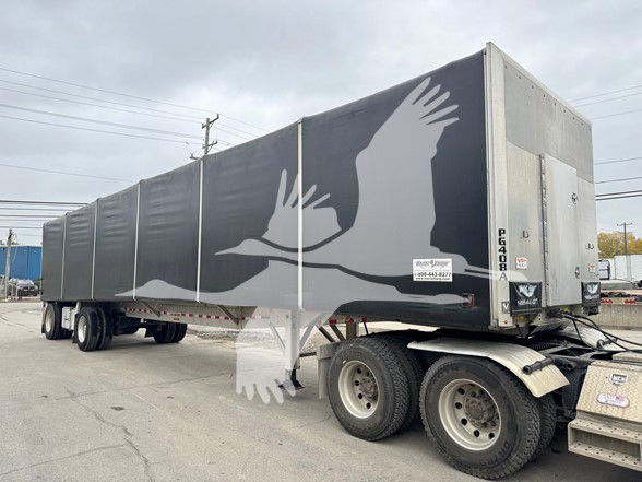 Trailer showing large bird graphic with wings on curtain side, rear access door, and dual rear wheels; 2021 Reitnouer Big Bubba curtainside trailer.
