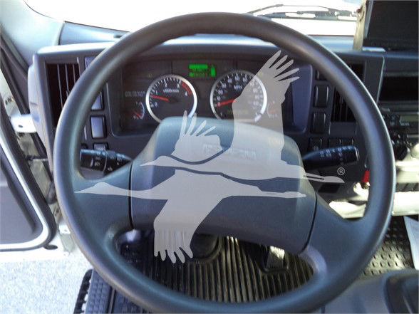 Isuzu truck dashboard steering wheel with instrument cluster and small green display; overlay watermark of a bird image obscures center.