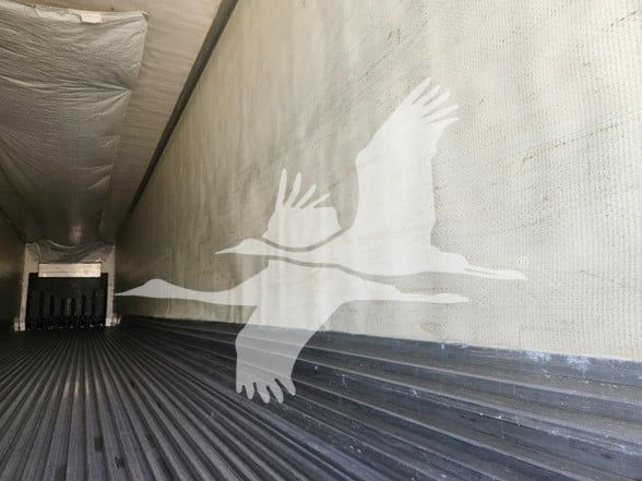 Trailer interior showing ribbed metal floor and insulated walls with a large white bird decal on the side.