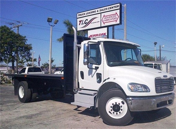 Flatbed tow truck with a 20 ft bed, front cab, and chrome bumper. Truck brand appears to be a white cab-over style with black flatbed, parked in a dealership lot.