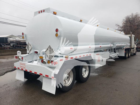 Heil 9200 gallon trough bottom Petro tank trailer shown from rear-left side with twin axles and white reflective tape.