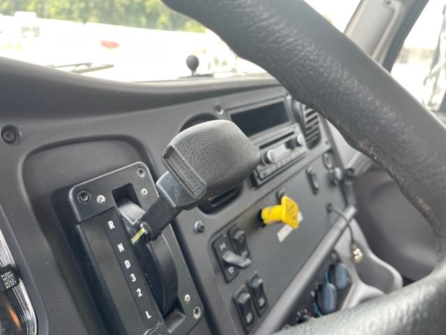 Truck interior showing gear selector for automatic transmission with letters P R N D 2 1 and yellow ignition key on dash.
