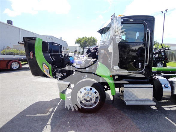 2022 Peterbilt 337 tow truck side view showing cab interior door and front wheel with chrome hub, green and black paint, hood open