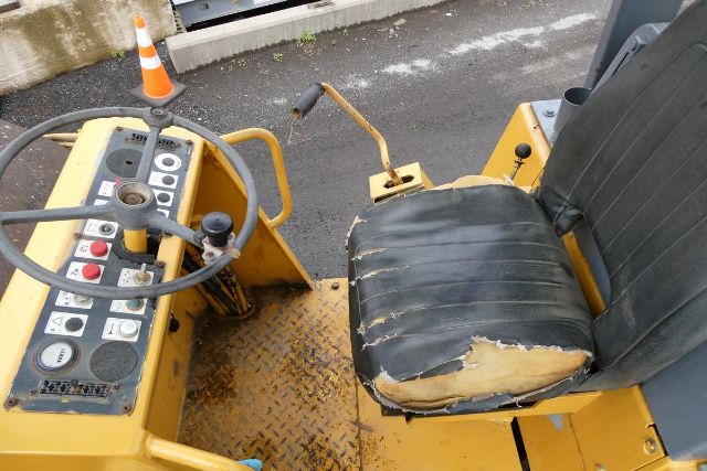 Operator seat and control panel of Bomag BW212D-2 compactor with steering wheel and worn seat.