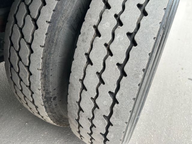 Truck dual tires in the front axle area with tread patterns visible.