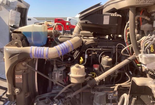 Peterbilt 579 engine bay showing intake hoses, coolant reservoir, and various engine components.
