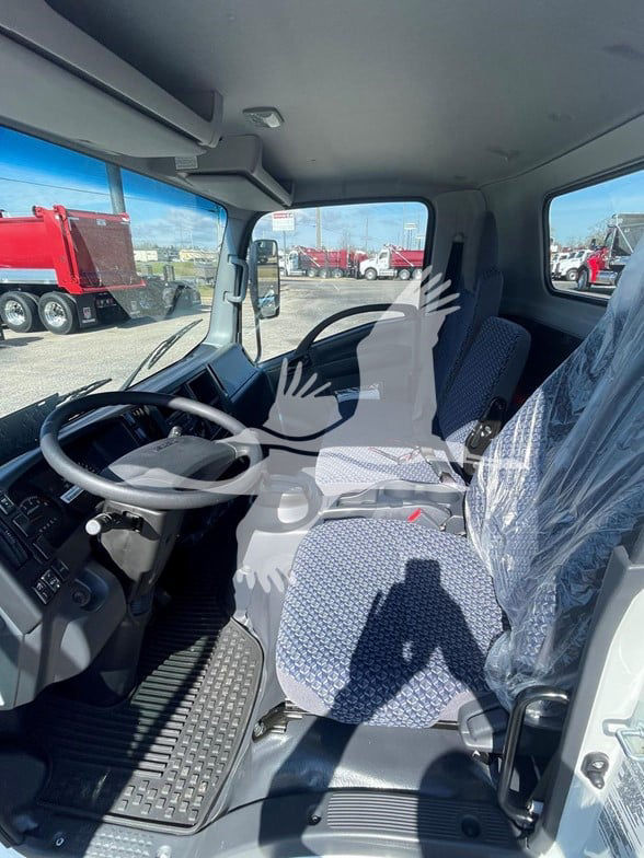 Isuzu NPR HD cab interior showing steering wheel, driver seat, and passenger seat with plastic covering and dashboard controls.