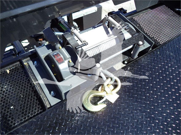 Tow winch assembly with motor and hook on textured steel deck, Isuzu FTR tow truck equipment visible.