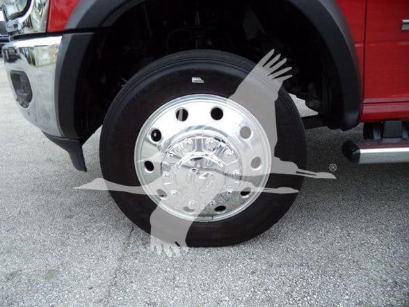 Ram 4500 wheel close-up showing chrome hubcap and black tire, red fender in background.