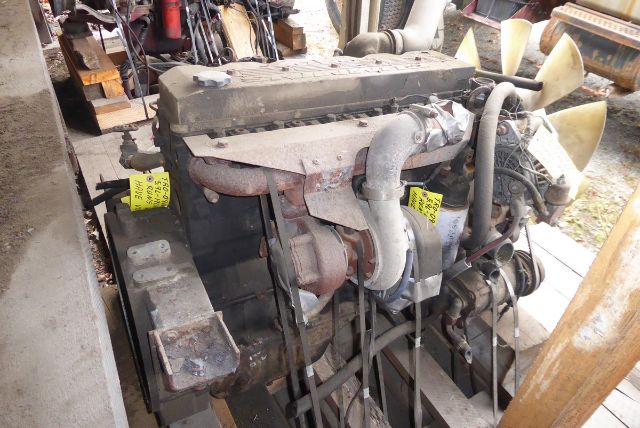 EFISB 5.9L Cummins engine on stand with belts and cooling fan visible, yellow tags on hoses, intake manifold, exhaust, and generator style setup.