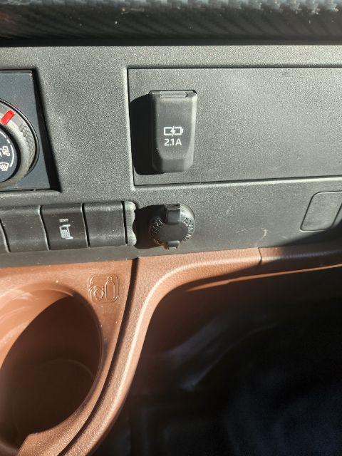 Dashboard area of a 2025 Hino L6 showing a USB/aux power input labeled 2.1A port and auxiliary controls with cup holder area.