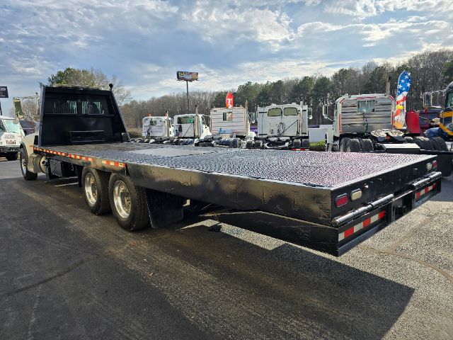 Peterbilt 348 rollback flatbed trailer showing aluminum diamond plate deck and dual rear axles.