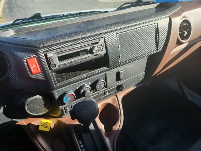 Dashboard of a 2025 Hino L6 box truck showing a radio unit, climate controls, ignition area, and gear shifter.