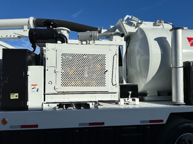 Industrial vacuum truck side view with generator and tank, equipment labels visible.