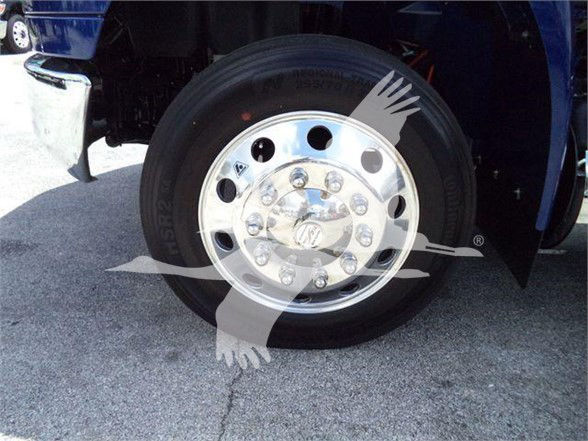 Tow truck wheel with polished chrome hubcap and black tire, portion of blue truck body visible.