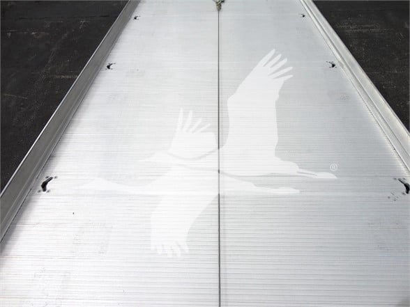 Stock photo of aluminum truck trailer deck with seam in center, light reflection, no text visible.
