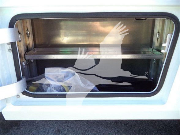 Ram 5500 truck cargo bed storage compartment with aluminum shelf and open hatch.