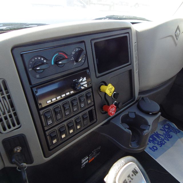 Interior of a 2016 International 7400 SBA 6X4 cab showing dashboard with climate controls, switches, ignition keys, and cup holders.