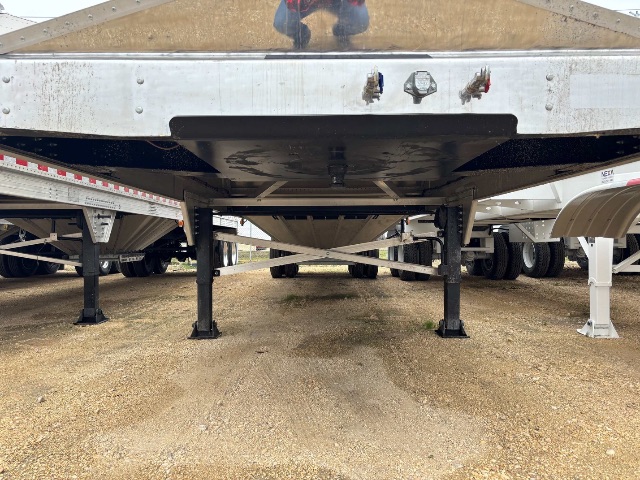 Underside view of a new aluminum sand/grain hopper trailer showing support legs and center frame.